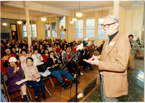 13 June 2019 Posted.
Lung “Pop” Chin, master storyteller and Chinatown elder, was beloved by the generations of community youth with whom he worked, especially for organizing sports teams and events. Mr. Chin, shown here having just addressed the room, was key to organizing the 1988 reunion; Museum of Chinese in America (MOCA) Institutional Archives. Lung “Pop” Chin，故事大师和唐人街长老，深受年轻人爱戴，特别是他组织的体育队和运动项目。照片中正在讲话的他是MOCA组织1988年第23公立小学聚会的关键人物；美国华人博物馆（MOCA）机构档案