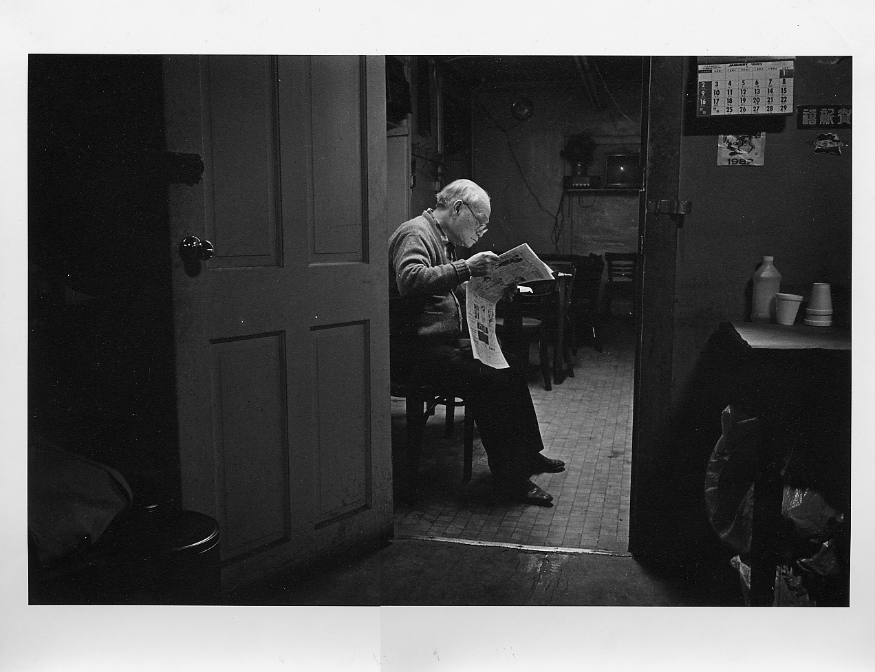 04 June 2019 Posted.
An old Man Reading in a Bachelor Apartment located ae 68 Byard Street, Photograph taken by Bud Glick. Museum of Chinese in America (MOCA) Collection.
一位老人在位于摆也街68号的单身公寓读报纸，照片由Bud Glick拍摄，美国华人博物馆（MOCA）馆藏