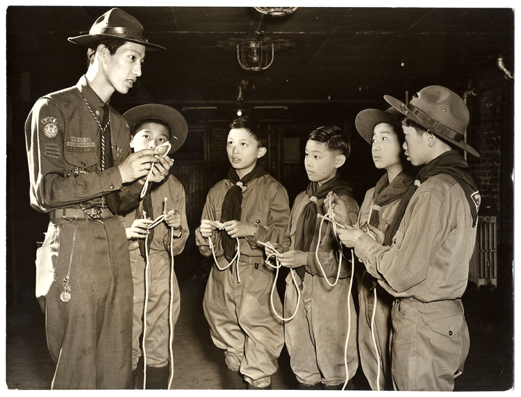 22 October 2019 Posted. 
Assistant Scoutmaster Horace Eng teaching a group of five scouts how to tie knots, 1942, Courtesy Kenneth & Helen Chan, Museum of Chinese in America (MOCA) Collection.
助理童子军英负责人Horace Eng正在教五位童子军成员如何系绳结，1942年，Kenneth & Helen Chan捐赠，美国华人博物馆（MOCA）馆藏