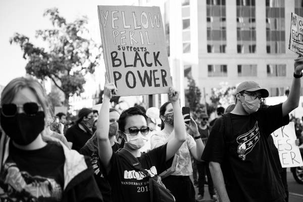Asians for Black Lives: An unnamed woman at a Black Lives Matter rally near the White House, Washington DC. She is holding a sign that says “Yellow Peril Supports Black Power.”  Photograph by Mengyu Dong