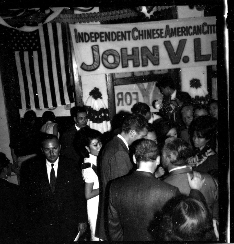 2000.020.041 Crowd of people gathered under an American flag and banner that reads "Independent Chinese American Citizens of New York City for John V. Lindsay." 人群聚集在美国国旗和写着 “纽约市独立华裔美国公民支持约翰·V·林赛（John V. Lindsay）”的横幅下。