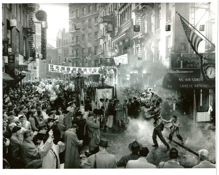 2015.043.032 Crowds flood the streets to see a lion dance outside the Chinese Rathskeller Restaurant on 45 Mott Street during a Chinese Lunar New Year Celebration. Other shops on the street include Pagoda Restaurant, Lee's Restaurant, Typond & Lee, Po On Co. It is a grand celebration with balloons, confetti, firecrackers, and a parade with dancers and portable shrines, undated. Courtesy of Eric Y. Ng, Museum of Chinese in America (MOCA) Collection. 2015.043.032 在纽约华人农历新年庆祝活动期间，人群涌入街道，观看位于勿街 45 号的中国 Rathskeller 餐厅外的舞狮。街上的其他商店包括 Pagoda 餐厅、Lee's 餐厅、Typond & Lee、Po On Co.。这是一个盛大的庆祝活动，有气球、五彩纸屑、鞭炮，还有舞者和便携式神龛的游行，日期不详。由伍锐贤提供，美国华人博物馆 (MOCA) 馆藏。