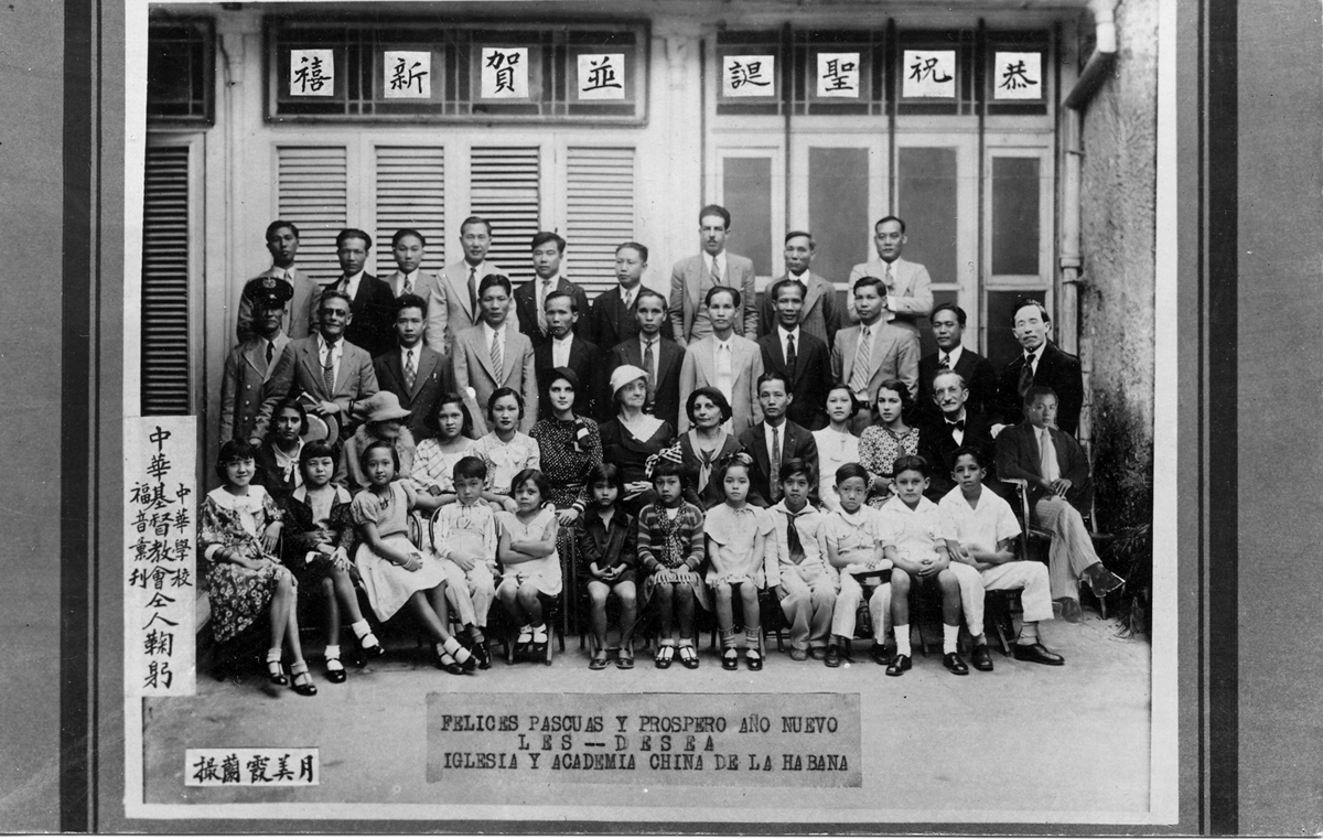 996.047.002 Sepia-toned group photo of the Chinese Church and Academy of Havana (Iglesia y Academia China de la Habana, or Zhonghua xuexiao/Zhonghua jidu jiaohui). Aurora Len (née Aurora Tang) sits in the front row, first from left. Spanish text on the photo reads: “Felices pascuas y prospero año nuevo, les desea, Iglesia y Academia China de la Habana.” Courtesy of Edwin K. Len, Museum of Chinese in America (MOCA) Collection.哈瓦那华人教会和学院（Iglesia y Academia China de la Habana，或中华学校/中华基督教会）的棕褐色调的合影。 Aurora Len (née Aurora Tang) 坐在前排，左起第一位。照片上的西班牙文写道：“祝您复活节快乐，新年快乐，哈瓦那华人教会和学院。”由Edwin K. Len 捐赠，美国华人博物馆 (MOCA) 馆藏。