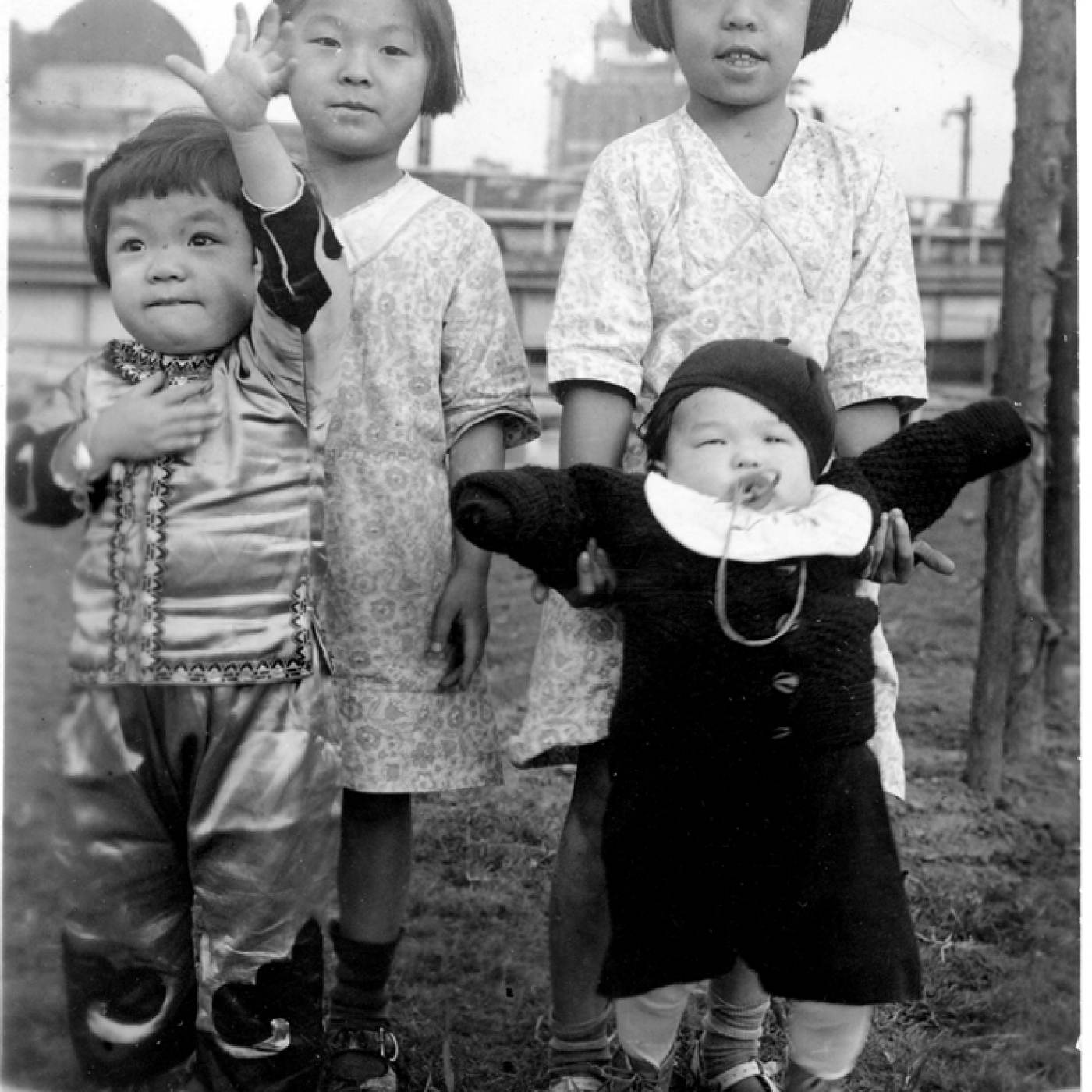2004.080.006 Fannie (right) is holding her younger sister, Alice, and standing next to her sister Effie, who is also holding onto another child. The year is 1938. They are in Police Athletic League Park, which was torn down during the building of the Confucius Plaza apartment buildings. Courtesy of Fannie Lui, Museum of Chinese in America (MOCA) Collection. Fannie（右）抱着她的妹妹Alice，站在她的妹妹Effie 旁边，Effie 也抱着另一个孩子。这一年是1938年，他们在警察田联公园内，该公园在孔子大厦公寓楼的建设中被拆除。由Fannie Lui 捐赠，美国华人博物馆 (MOCA) 馆藏。