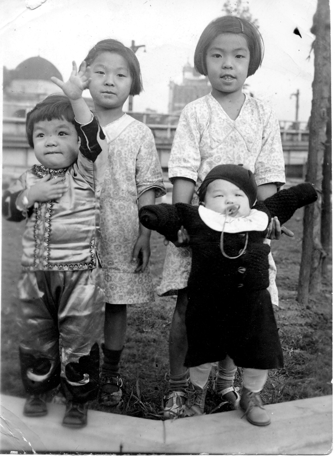 2004.080.006 Fannie (right) is holding her younger sister, Alice, and standing next to her sister Effie, who is also holding onto another child. The year is 1938. They are in Police Athletic League Park, which was torn down during the building of the Confucius Plaza apartment buildings. Courtesy of Fannie Lui, Museum of Chinese in America (MOCA) Collection. Fannie（右）抱着她的妹妹Alice，站在她的妹妹Effie 旁边，Effie 也抱着另一个孩子。这一年是1938年，他们在警察田联公园内，该公园在孔子大厦公寓楼的建设中被拆除。由Fannie Lui 捐赠，美国华人博物馆 (MOCA) 馆藏。