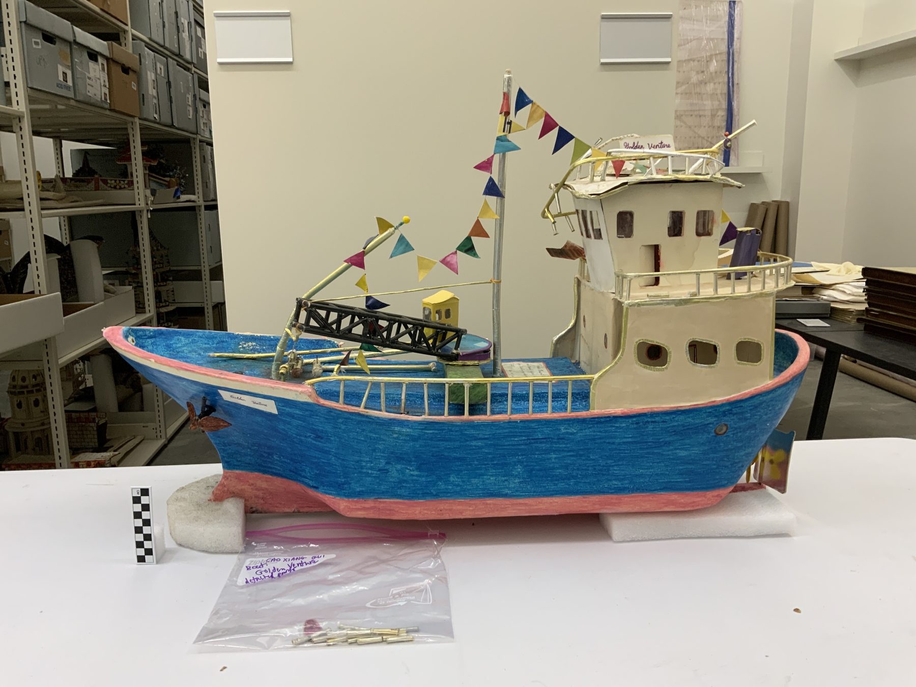 1996.061.045 Paper sculpture of the Golden Venture ship made by one of the refugees detained after this vessel ran aground at Rockaway Beach, Queens in 1993. Papier-mâché and colored marker, 1993-1996. Photograph taken post-fire. Museum of Chinese in America (MOCA) Fly to Freedom Collection.