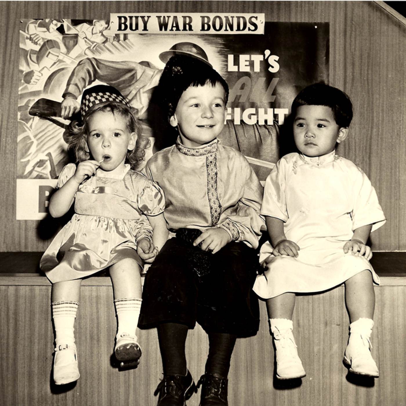 2004.029.007 Three children—one Scottish, one Russian, and one Chinese—were chosen by artist Margery Ryerson to be models for paintings to be used by the Ninth Federal Savings and Loan Association at 1457 Broadway, New York, NY to boost the sale of war bonds. The children are, from left to right: Susan Murray, of Stillwell Avenue, Brooklyn; Andriusha Branitzka, of 57th Street, Manhattan; and Virginia Chin (née Lee), of 73 Mulberry Street, Manhattan. Photograph taken by Larry Gordon. Courtesy of Virginia S. Chin, Museum of Chinese in America (MOCA) Collection. 三个孩子—一个苏格兰人、一个俄罗斯人和一个中国人—被艺术家 Margery Ryerson 选为纽约州百老汇 1457 号第九联邦储蓄和贷款协会的绘画模特，以促进出售战争债券。孩子们从左到右是：布鲁克林斯蒂威尔大道的苏珊·默里；曼哈顿第 57 街的 Andriusha Branitzka；曼哈顿茂比利街 73 号的 Virginia Chin (née Lee)。照片由拉里·戈登拍摄。由Virginia S. Chin捐赠，美国华人博物馆 (MOCA) 馆藏。