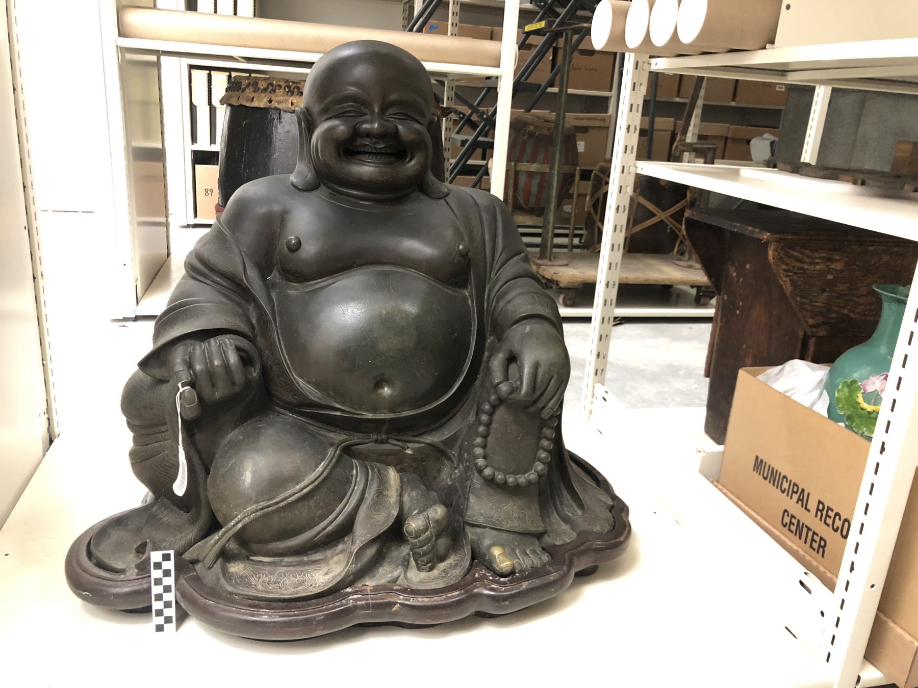 T-2034874 and T-2035267 Large bronze Laughing Buddha from the Savoy Inn, a Chinese restaurant opened by Edward L. Hong in Freeport, Long Island in 1933. Measures approximately 4 ft. tall x 3 ft wide. Photograph taken post-fire. Courtesy of Rocky Chin, Museum of Chinese in America (MOCA) Collection.