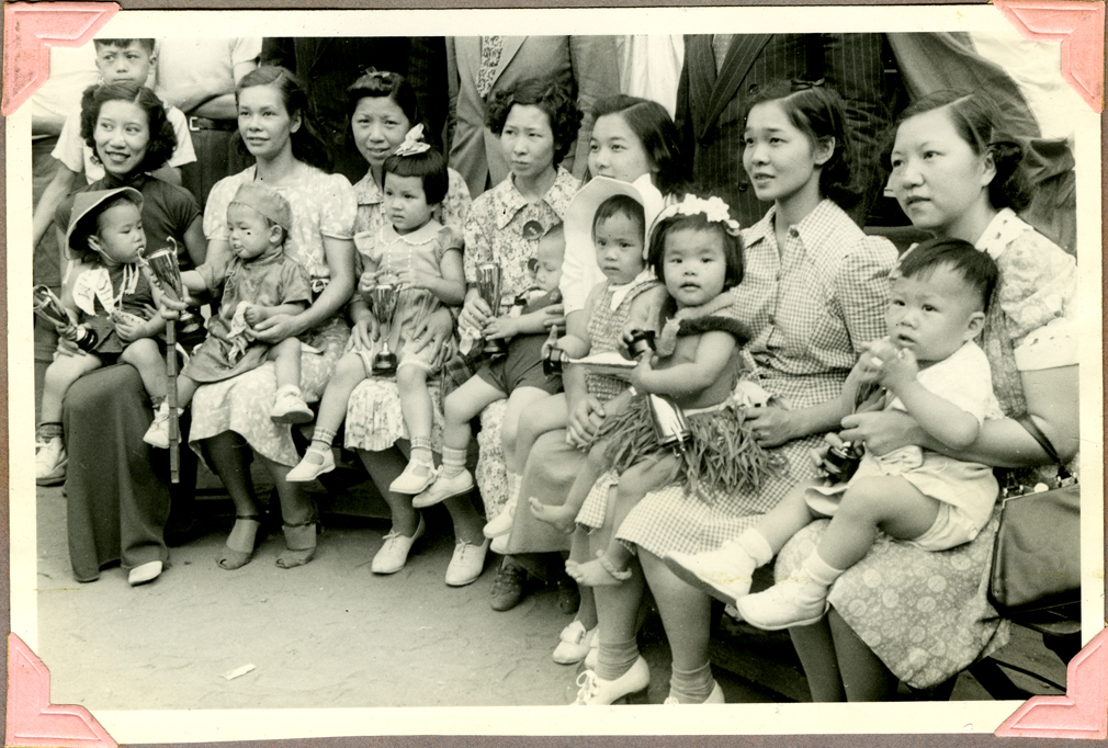 2012.002.002 A group photograph of the participants in the New York City Chinatown baby contest held on June 17, 1939 in Columbus park. Second from the right are mother and daughter Vivian Dai and Meling Dai (18 months). Third from the right are Meme Chen with her daughter Jaqueline Young (2 years). First from the left are May Moy with Patricia Moy (2 years). Third from left are Grace Lee Mok and her daughter Jade Mok, who won the prize for healthiest girl. Pictured at far right is Rose Lee Liu, wife of Dr. Arthur Liu, with her son Allan Liu. The Commissioner of Health and policemen, standing behind them, were the guests of honor. Courtesy of Meiling Dai, Museum of Chinese in America (MOCA) Collection.