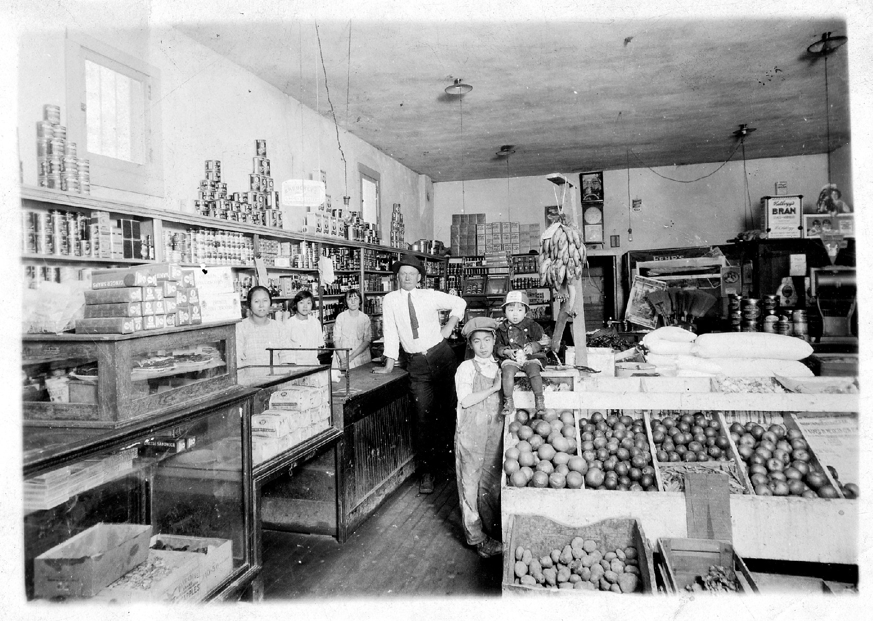 2001.015.009 The Tang family and their family store, Ong Yee Lung Grocery Store, in Arizona in 1922. From left to right are: Mary (Fong Shee Tang), Mabel Tang, Eleanor (friend), salesman, Sing John Tang, and Mae Tang. Courtesy of Lois Tang Leung, Museum of Chinese in America (MOCA) Collection. 1922 年在亚利桑那州的唐氏家族和他们的家族商店，Ong Yee Lung杂货店。从左到右分别是：玛丽（Fong Shee Tang）、Mabel Tang、Eleanor（朋友）、推销员、Sing John Tang 和Mae Tang。由Lois Tang Leung 捐赠，美国华人博物馆 (MOCA) 馆藏。