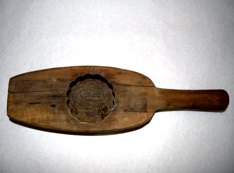 2018.001.001 A wooden mooncake mold that was used at the Nom Wah Bakery at 15 Doyer Street in New York. Courtesy of Wilson Tang, Museum of Chinese in America (MOCA) Collection. 在纽约宰也街15号的南华茶室使用的木质月饼模具。由Wilson Tang捐赠，美国华人博物馆（MOCA）馆藏。 