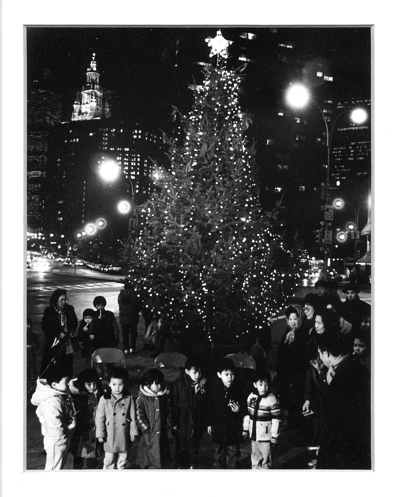 2011.046.008 This photograph, taken by Poon Waterfield, shows families at the celebration of the first Christmas tree ever in Chatham Square, December 1986. Courtesy of Poon Waterfield, Museum of Chinese in America (MOCA) Faces of Chinatown Collection.