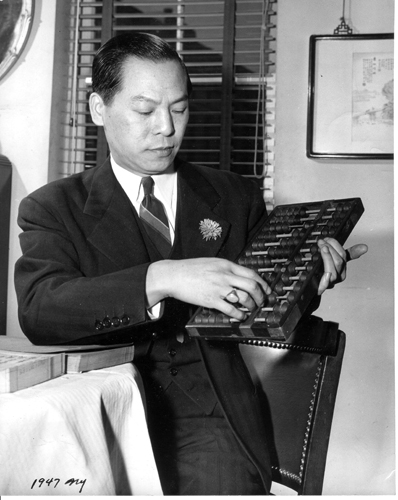 位于勿街44号的大同酒家老板陈瑞炳身着西装，手持算盘。图片由陈雪瑛捐赠，美国华人博物馆（MOCA）馆藏。